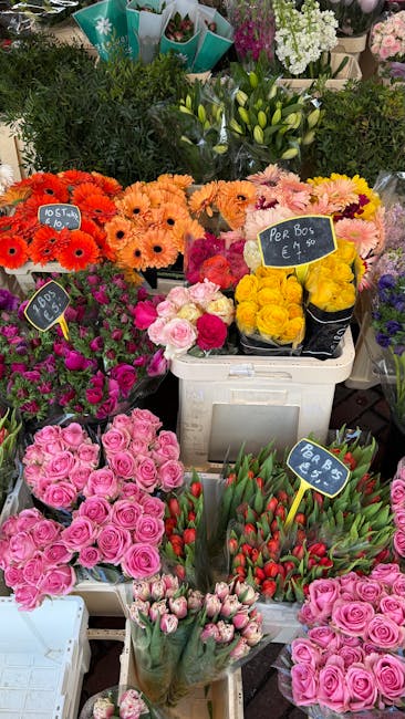 A vibrant display of fresh floral bouquets and potted plants at a flower shop, featuring a variety of colorful flowers including pink roses, red tulips, yellow roses, orange Gerbera daisies, and white